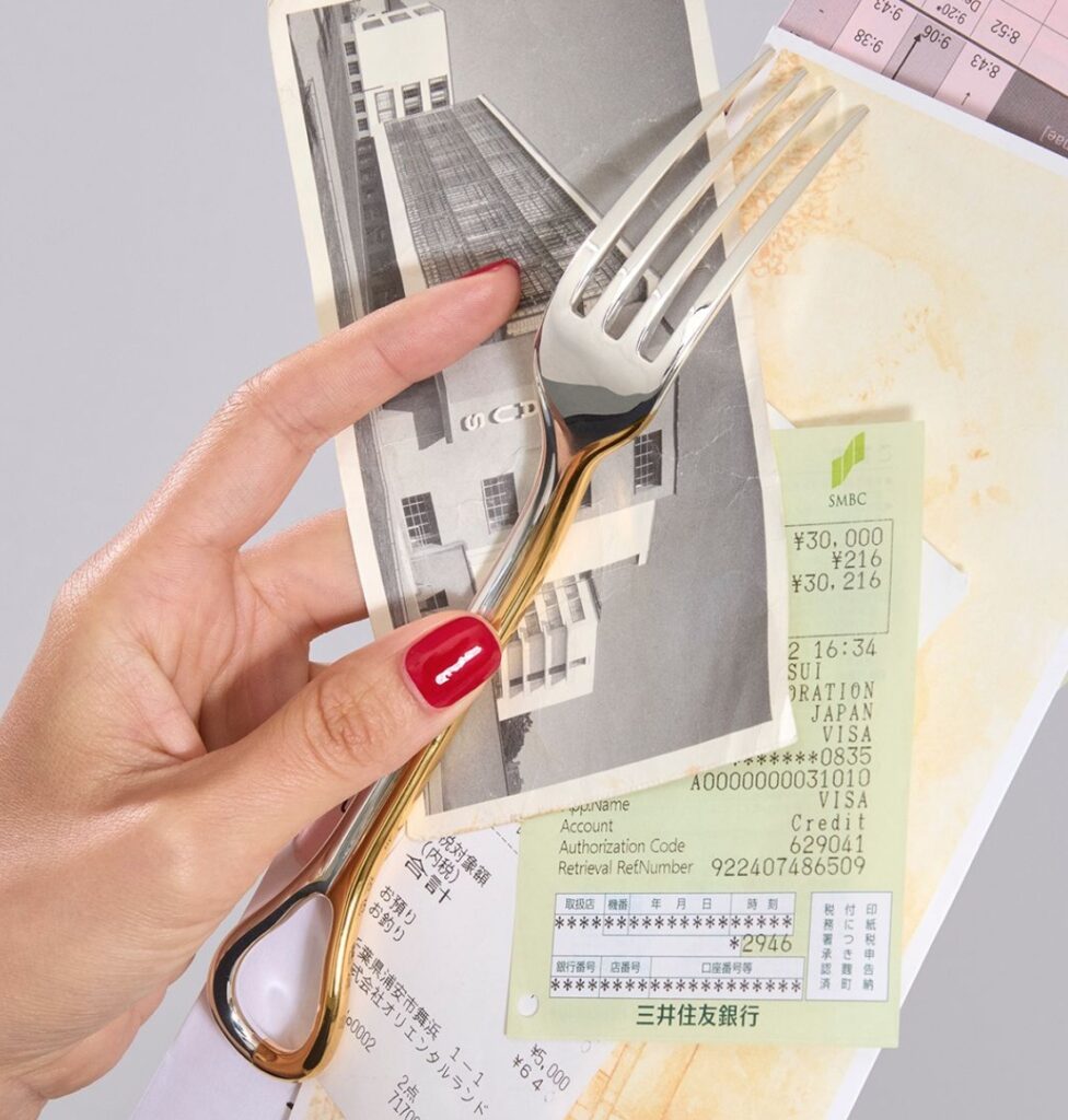 Fork detail with hand holding various receipts and photo of a building
