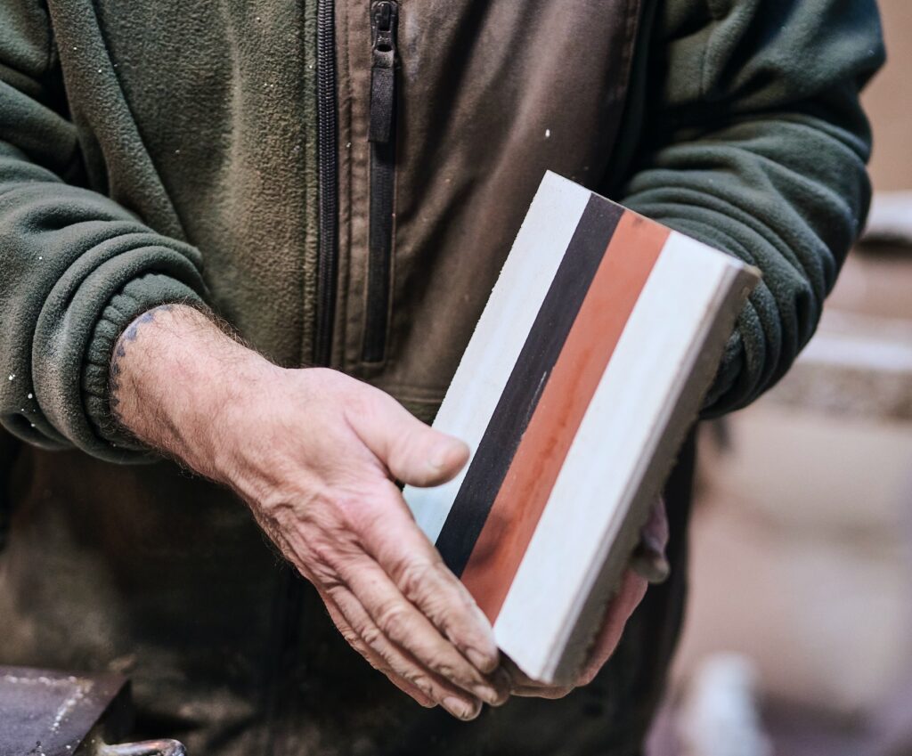 Detail of man holding Tessieri tile in white, black, red stripes