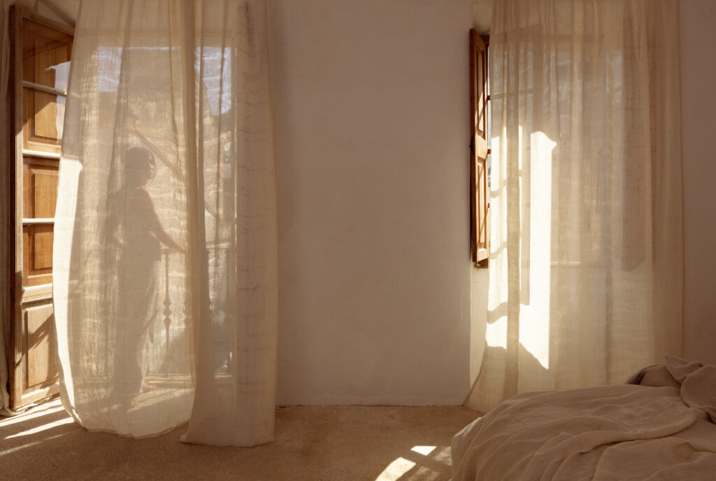 Cream sheer fabric in apartment with woman standing on balcony