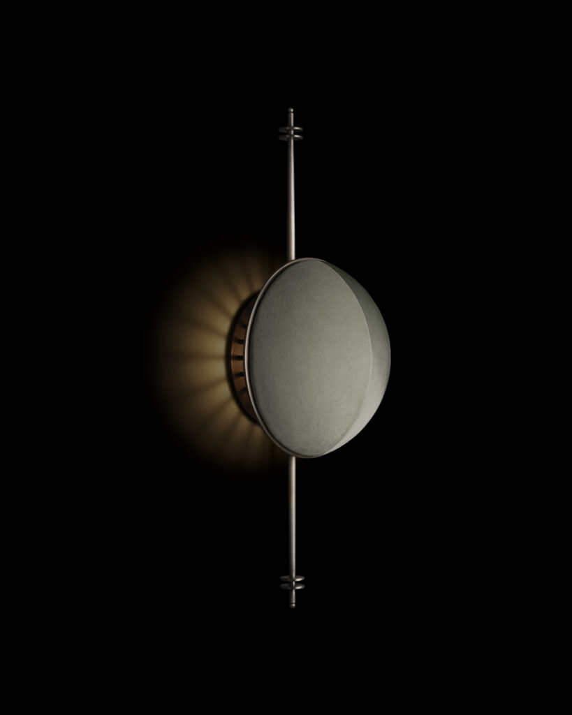 Side view of the Starlet Sconce reveals its suede-wrapped disc and brass armature, with light diffusing into a soft, radiant halo.