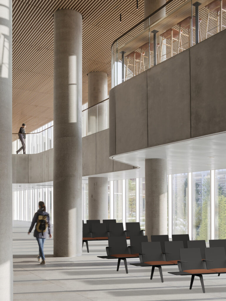 Pausit benches installed in a contemporary institutional lobby, with double-height ceilings, curved glazing, and warm-toned concrete columns, demonstrating real-world application.