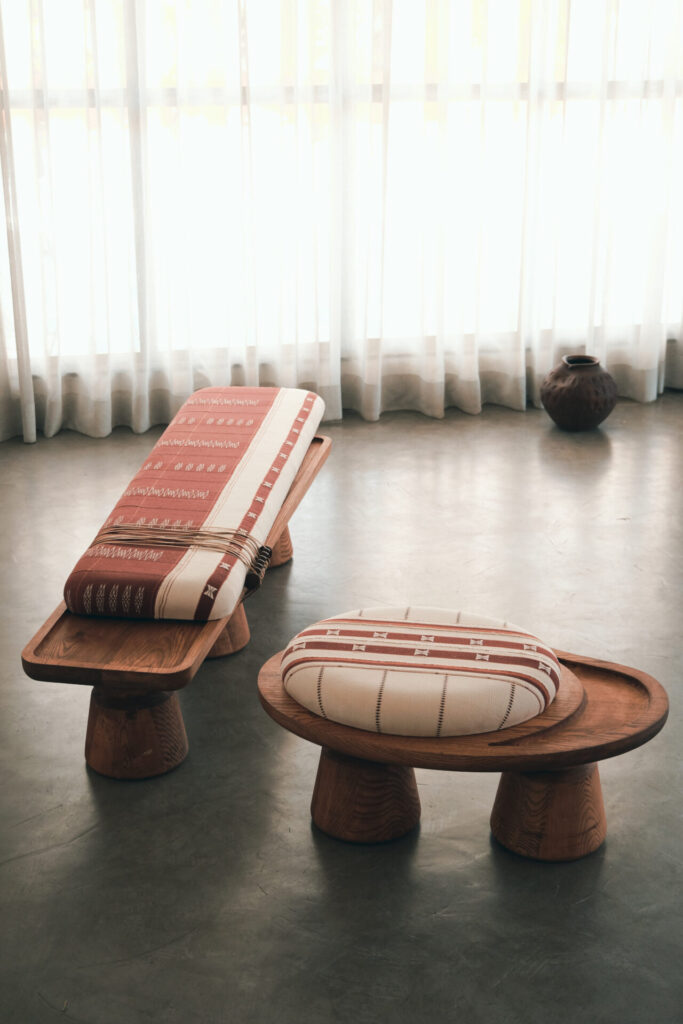 Wooden bench and matching ottoman with handwoven patterned seats in front of sheer drapes, blending craft and modern minimalism.