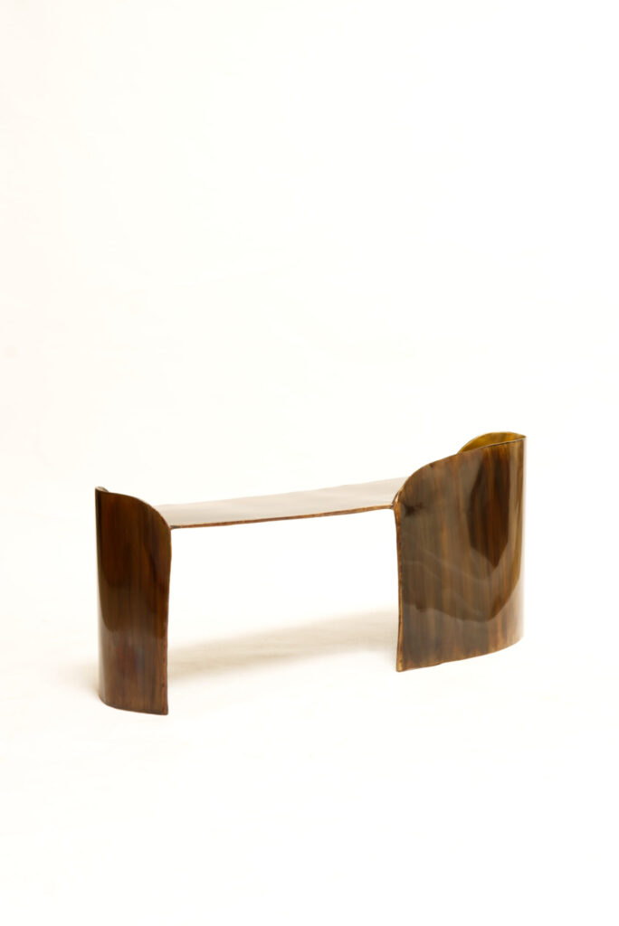 Minimalist brass bench from the Calle Collection, its folded form appearing both solid and weightless. 