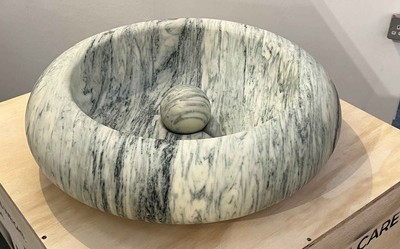 The Roll Ball Sink in veined marble, featuring a polished orb nested in its hollow form—part sculpture, part functional basin.