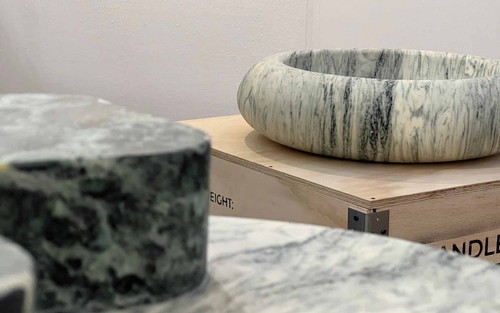Close-up of sculptural marble sinks by Mark Mitchell, their smooth circular forms resembling carved stone vessels.