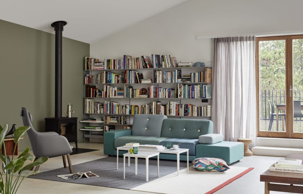 A green Polder Sofa sits in a cozy library-style interior, paired with a white coffee table and surrounded by bookshelves, balancing function with expressive design.