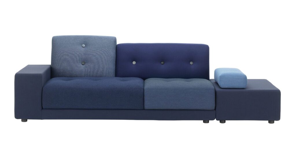 Front-facing view of Vitra’s Polder Sofa in layered blue upholstery with mismatched textures, oversized horn buttons, and an extended platform for books or trays.