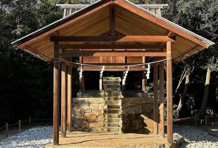 Full view of the Go’o Shrine framed by its wooden structure, with Sugimoto’s crystal-like staircase glowing at the center, surrounded by a bed of white stones beneath the trees.