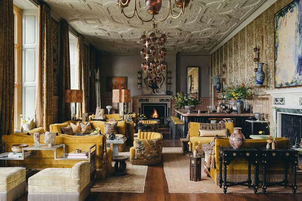Eclectic interior lounge at Estelle Manor with velvet seating, patterned textiles, chandeliers, and a roaring fireplace.