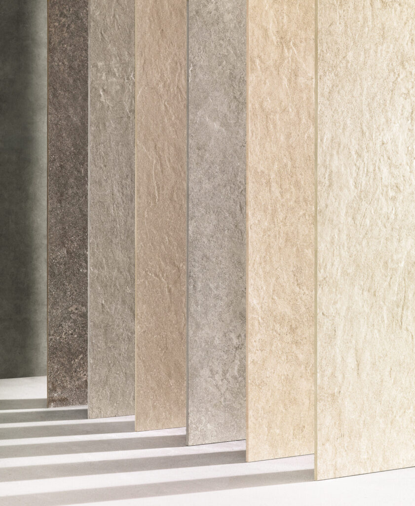 An array of stone-look porcelain tiles in a natural gradient from charcoal to ivory, each revealing nuanced texture and color variation reminiscent of quarried stone.