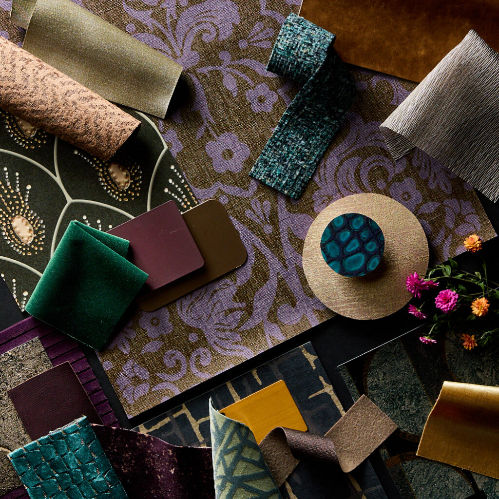 A richly layered materials board mixes deep violet damask, teal velvet, metallic cork, and warm ochre tones, embodying the tactile richness of today’s hospitality color trends.