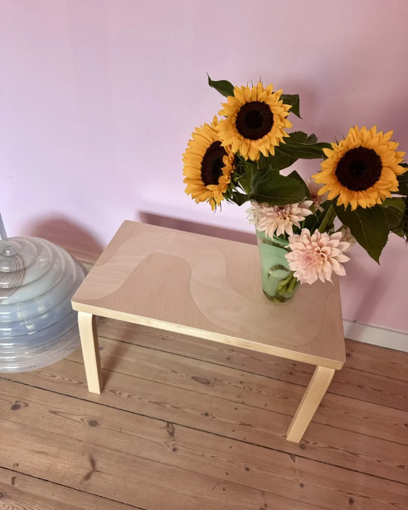 Bench and stool arrangement from the Artek–Marimekko series, where patterned furniture reads as light, layered wood surfaces in a calm studio setting.