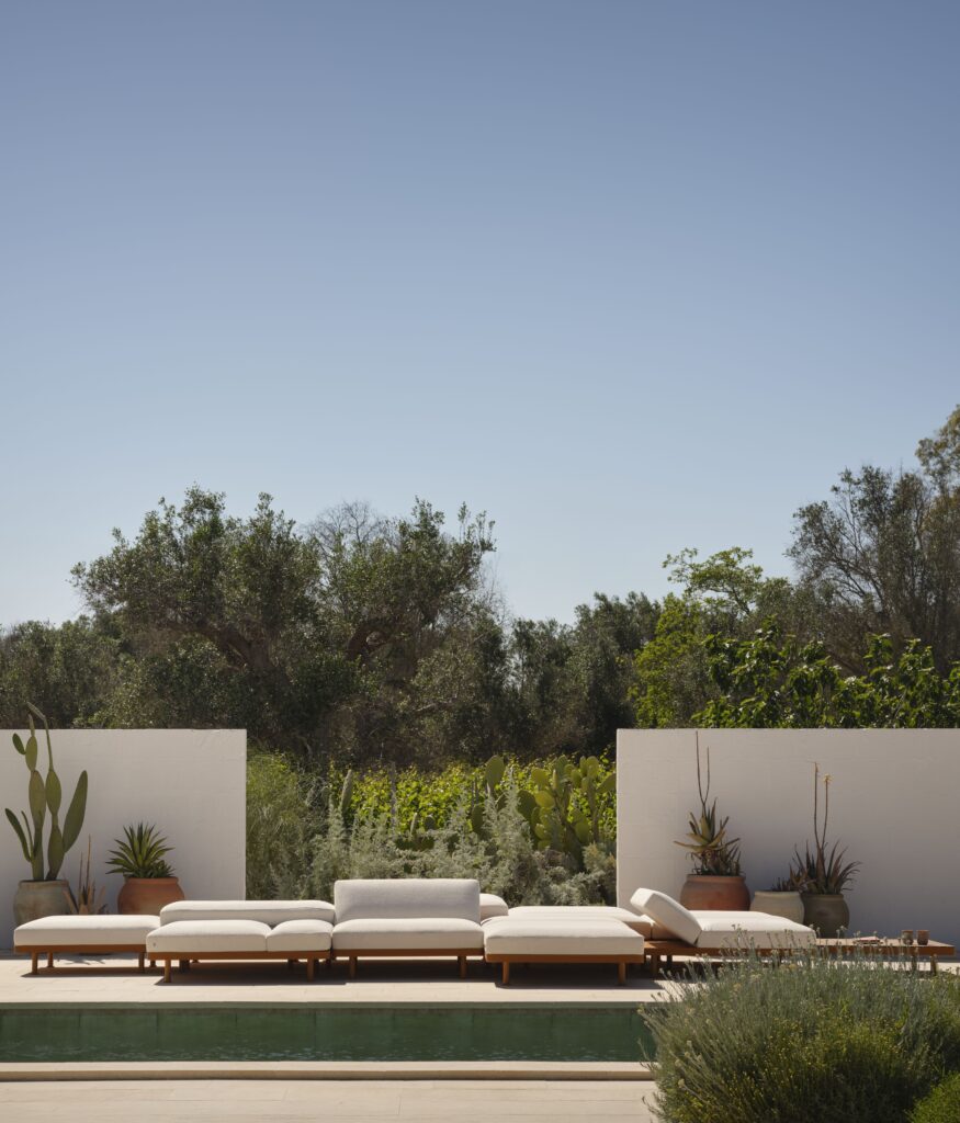 Linear arrangement of the Unduetre system beside a pool, showing how outdoor modular seating creates calm structure within a landscaped terrace.