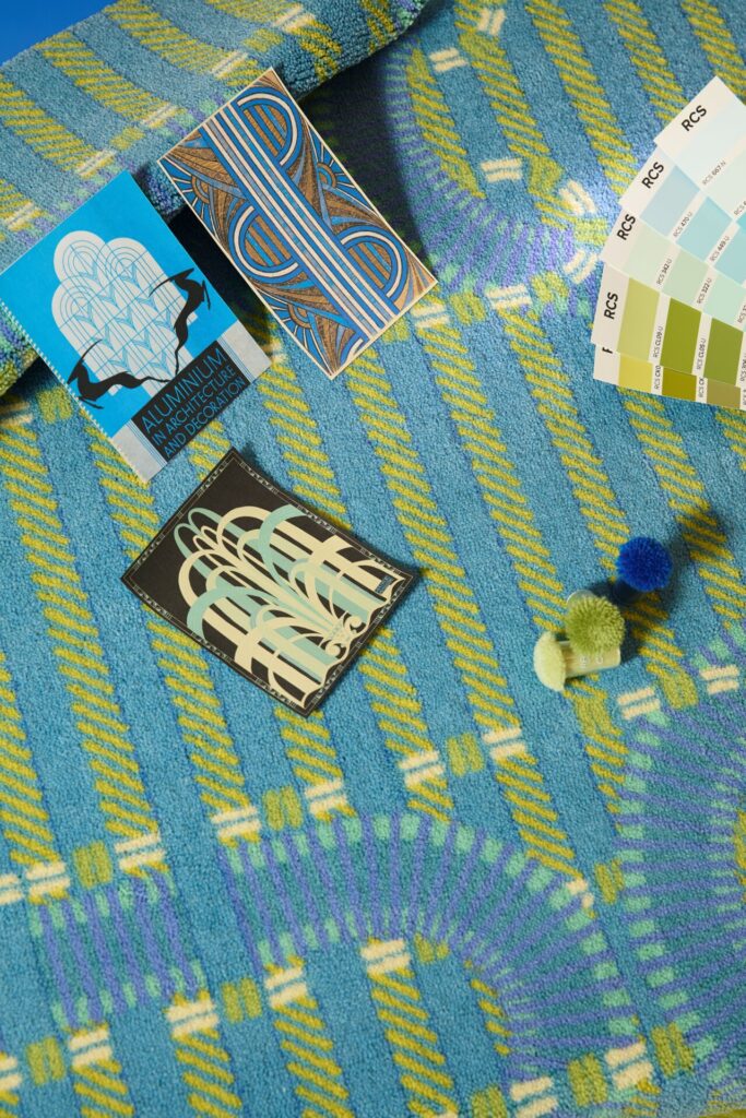 A vivid blue-and-lime Champs rug becomes a working surface for color studies: Art Deco reference cards, pom swatches, and an RCS palette fan out across the tufted pattern, revealing how structure and intuition shape the design language behind Ritmi.