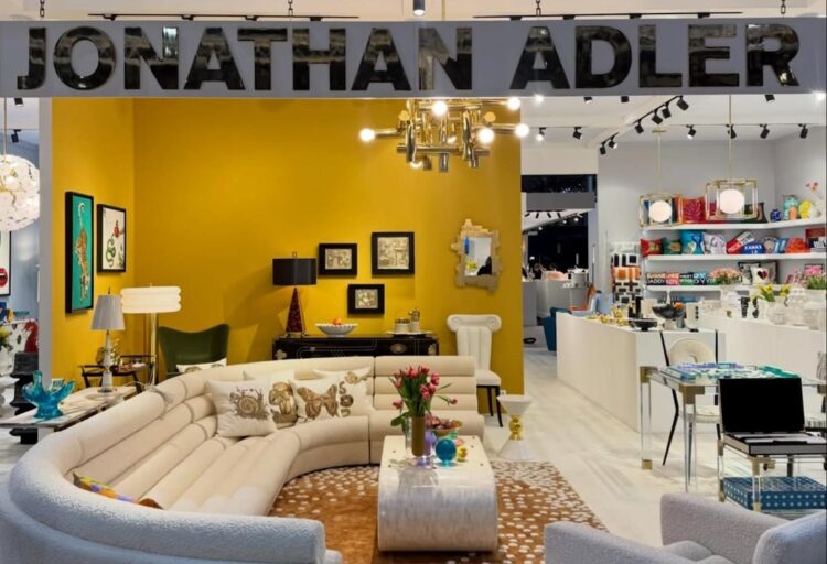 Wide view of Jonathan Adler’s Maison&Objet 2026 booth reading as a complete interior, with curved seating, patterned rugs, layered lighting, and high-gloss accents defining a cohesive showroom environment.