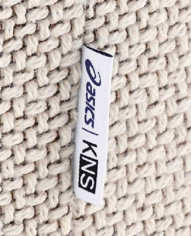 Close-up of textured upholstery fabric with KNS / ASICS collaboration tag, highlighting material detail and sustainable contract seating craftsmanship.