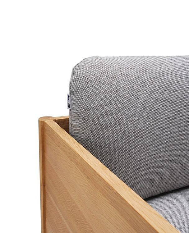 Close-up of the wood side panel and upholstered back cushion on the Castor Lobby Sofa, highlighting material contrast and the quiet durability of sustainable contract seating.