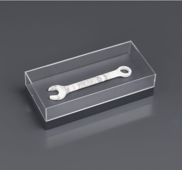 Combination wrench sculpted from veined white marble and displayed in an acrylic case, preserving its functional outline in solid stone.