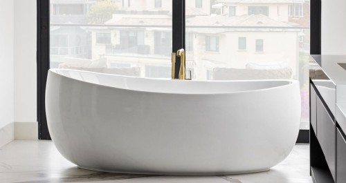 White sculptural bathtub design with an integrated whirlpool system, shown against large black-framed windows, where clean lines and concealed mechanics keep the bath visually quiet and refined.