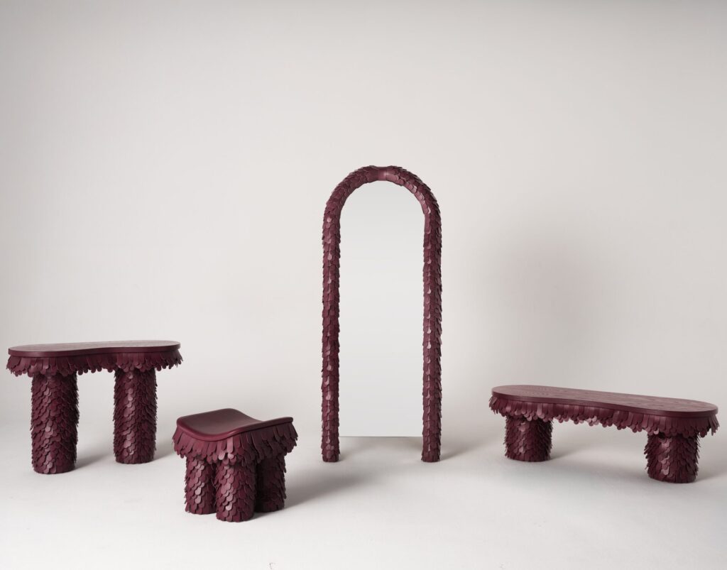 Uniqka’s Borgona collection displayed as sculptural furniture pieces at Maison&Objet 2026, featuring monochromatic benches, stools, and an arched mirror unified by layered texture and deep wine-toned finishes.