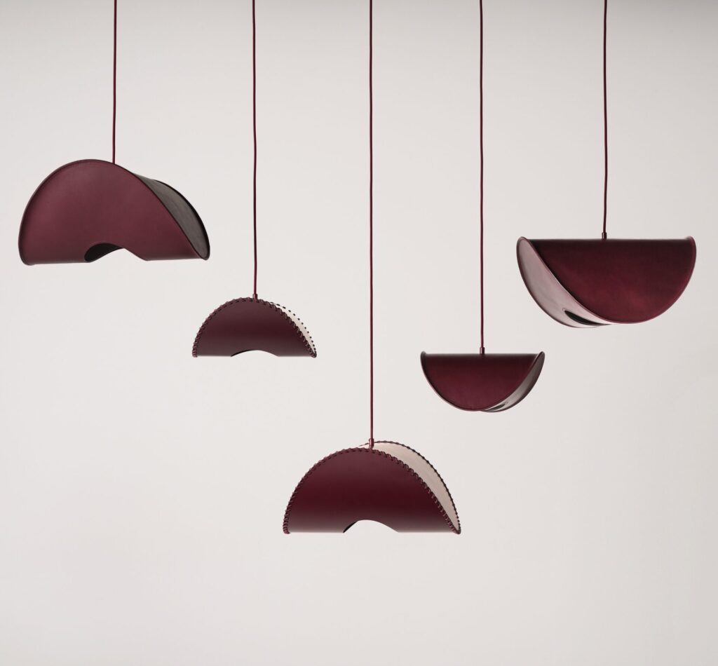 Suspended Borgona pendants by Uniqka arranged at varying heights, highlighting curved silhouettes and stitched detailing within a monochromatic lighting design installation at Maison&Objet 2026.