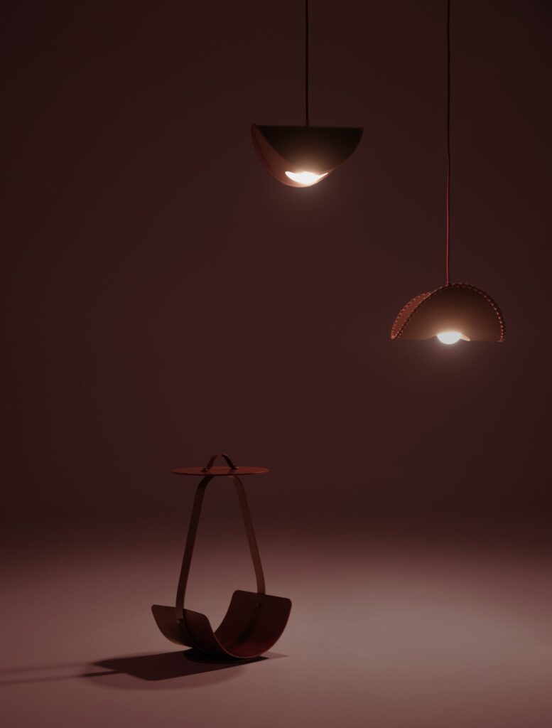 Borgona table and pendant lighting by Uniqka shown in low light, demonstrating how monochromatic burgundy finishes and sculptural forms create atmospheric lighting for hospitality interiors.
