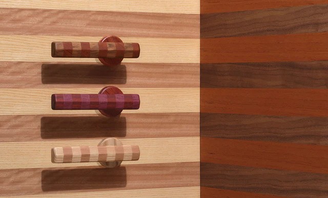 Wall-mounted display of striped wood door handles and circular pulls in varied timber tones, presented as a graphic composition of architectural door hardware.