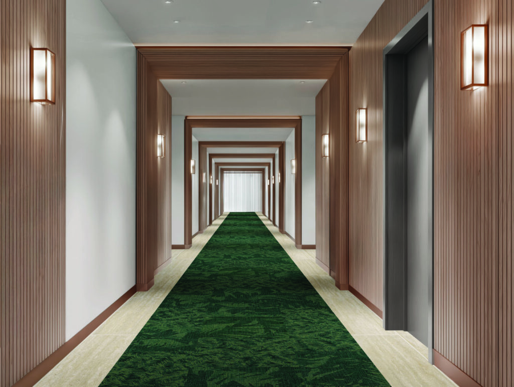 Hotel corridor featuring leafy green hospitality carpet runner framed by stone flooring and warm wood wall panels from Shaw Contract Hospitality ROAM collection.