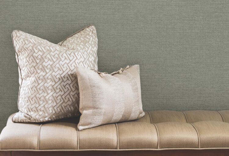 Green-toned performance wallcoverings with textile-like texture, complementing layered pillows and a leather bench