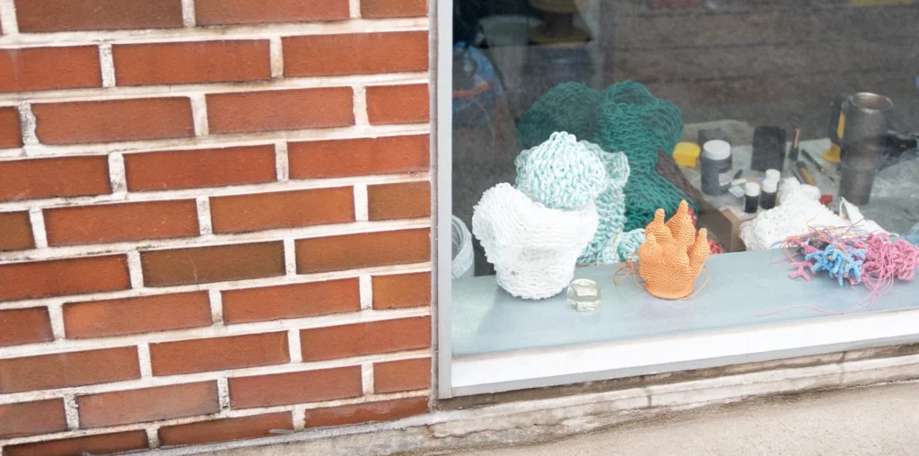 Knitted leather vessels and experimental forms displayed in a studio window, early studies for a sculptural lighting installation