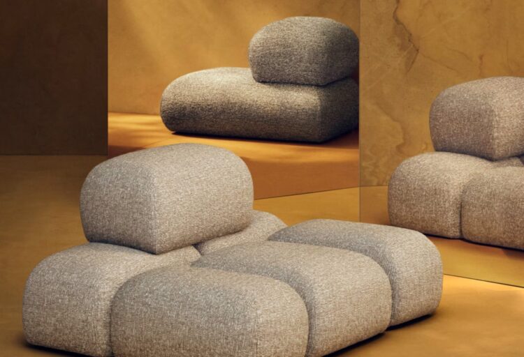 Modular furniture collection of pebble-soft boucle seating arranged as a low, flexible lounge, forming a sculptural sofa system within a historic interior.