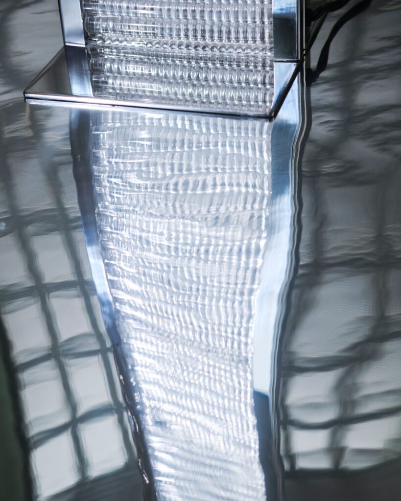 Close-up of rippled glass block reflecting light and architecture, emphasizing the material texture within a glass lighting installation.