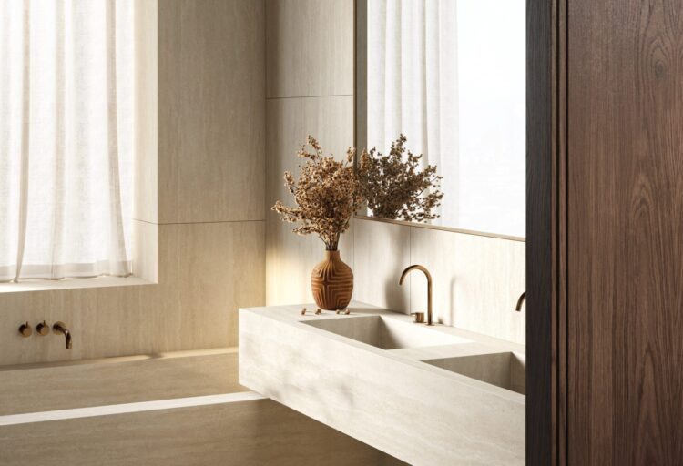 Minimal bathroom with floating double vanity in travertine porcelain slabs, soft daylight filtering through sheer curtains, and brushed brass fixtures emphasizing a calm, continuous surface.