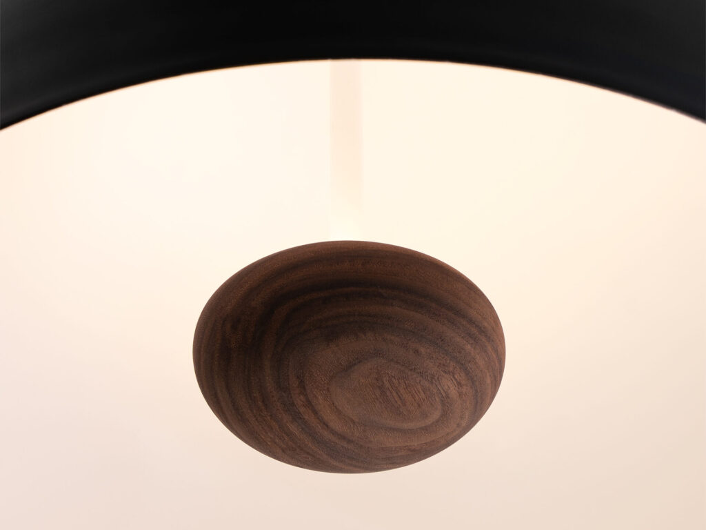 Decorative pendant lighting detail showing turned wood diffuser beneath a softly glowing dome, highlighting natural grain and warm illumination