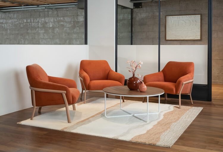 Three Talina lounge chairs by Arcadia in rust upholstery gathered around a low table, showcasing contract lounge seating with a soft architectural frame.