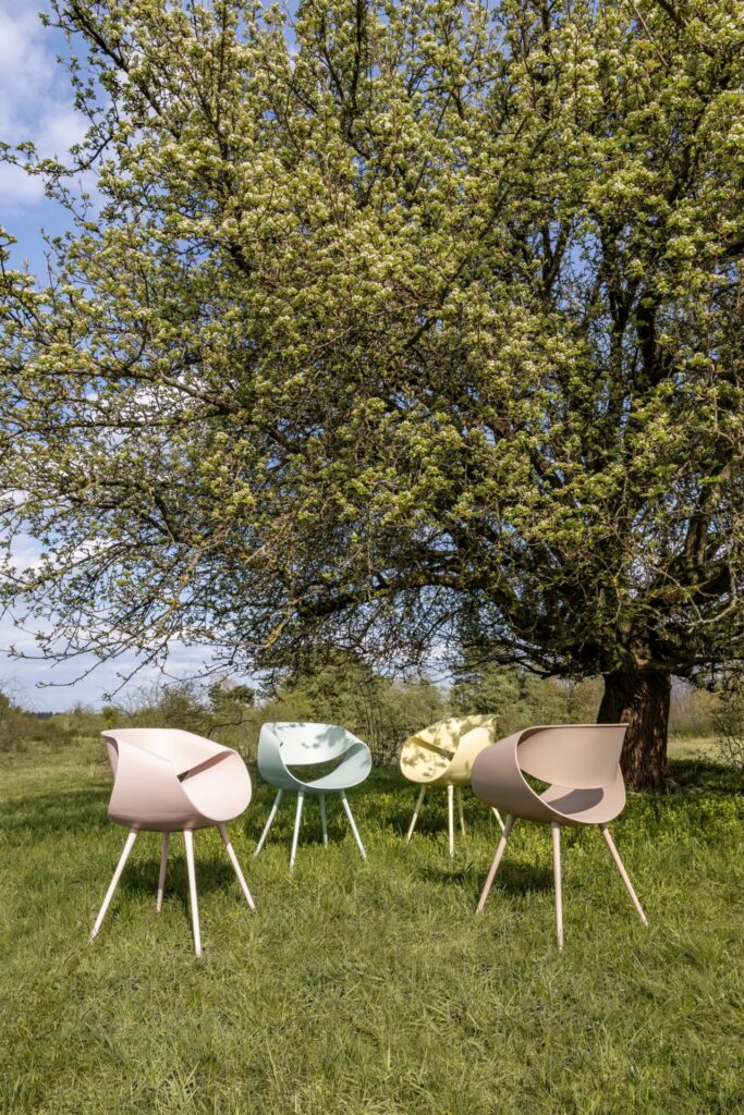 Sustainable seating in soft green tones, the Little Perillo ECO chair forms a continuous loop around a café table, blending recycled plastic design with light, open-air hospitality.