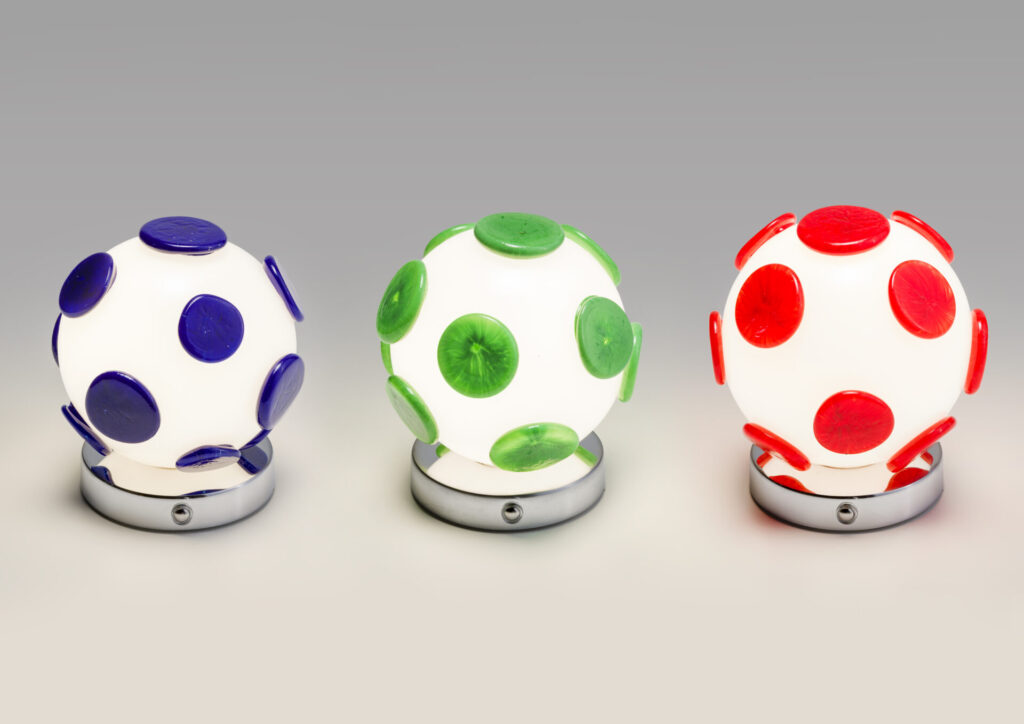 Three glowing Tripop portable rechargeable lamps by Matteo Cibic for Multiforme, featuring white Murano glass spheres dotted in cobalt blue, lime green, and bright red atop polished chrome bases.