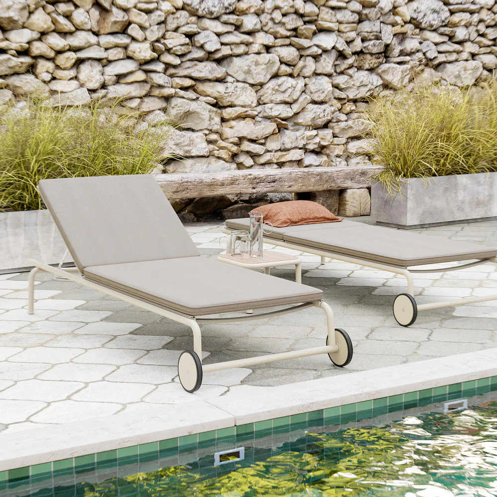 Minimal chaise lounges from the Campus Collection line a pool terrace, pairing powder-coated steel frames with weatherproof cushions and restrained outdoor design.