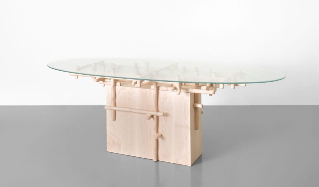 Sculptural wood dining table from Onno Adriaanse’s Hedera collection for Dilmos, featuring carved maple stems supporting an organic glass top.