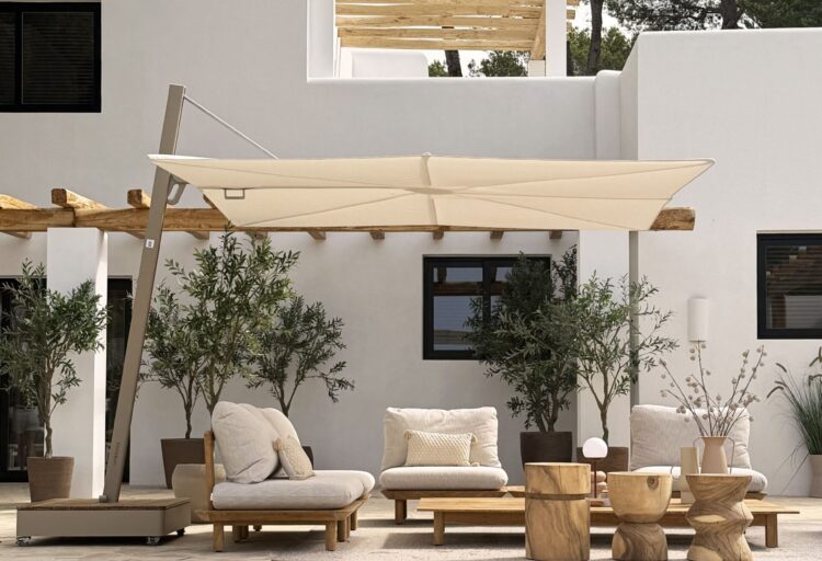 Umbrosa Versa cantilever umbrella beside a reflective pool, paired with minimalist outdoor lounge seating and warm wood accents in a resort-style courtyard.