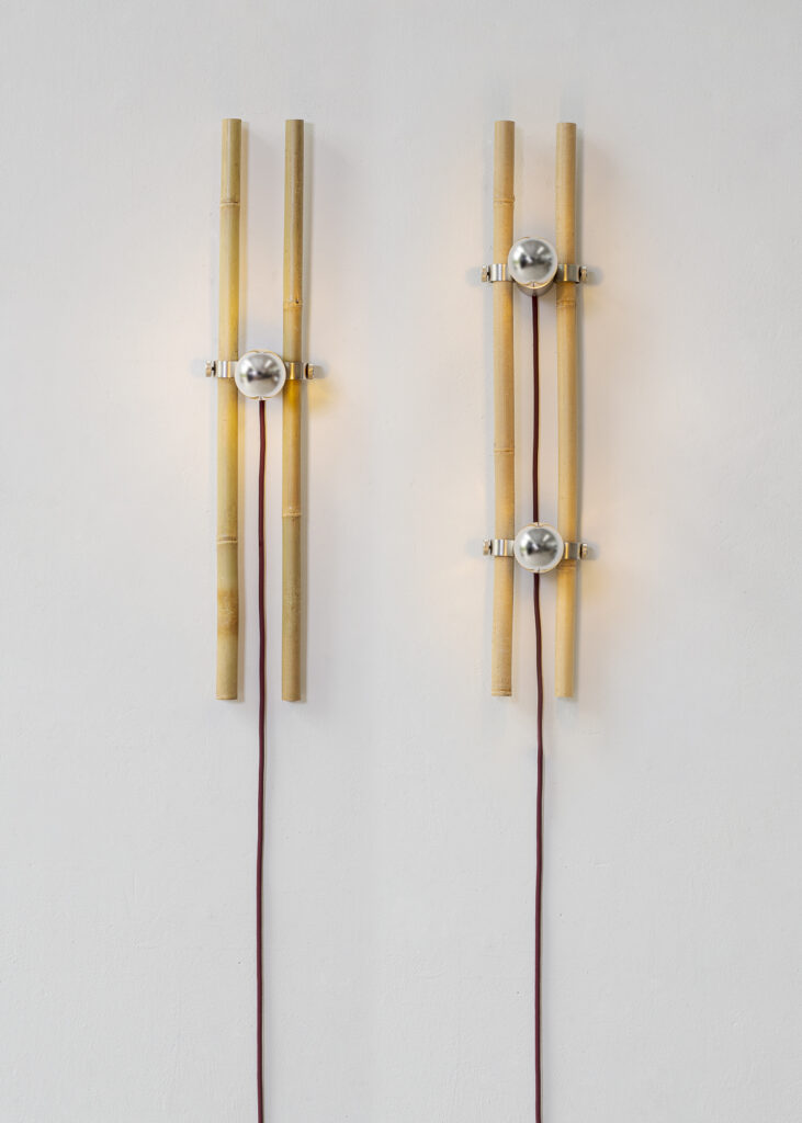 Pair of Bambù wall lamps by Gupica combine raw bamboo poles, brushed metal LED mounts, and exposed textile cords, showcasing natural material lighting with an industrial edge.