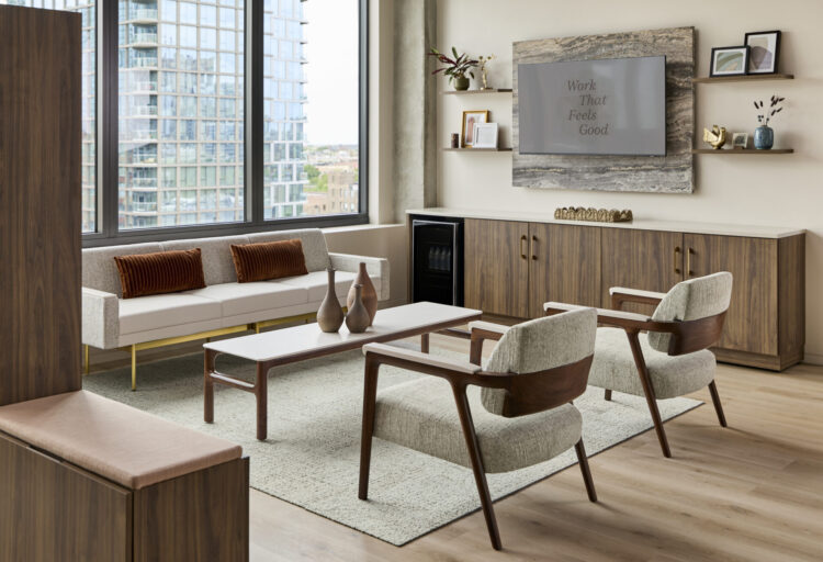 Lounge setting inside Kimball International's Chicago showroom with upholstered seating, wood casework, coffee table, and Work That Feels Good display.