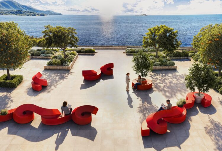 Bright red modular outdoor seating from the Spin collection creates sculptural gathering areas on a waterfront hospitality terrace.