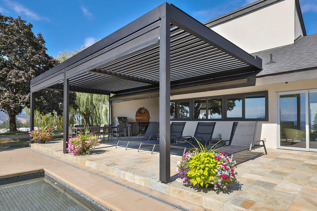 Freestanding Corradi Alba louvered roof pergola shades a poolside terrace, its adjustable aluminum louvers creating flexible sun and weather protection for outdoor living.