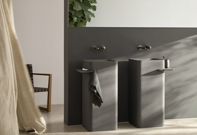Two Hastings Cuadra JOY pedestal sinks in matte charcoal with integrated shelves and wall-mounted faucets in a contemporary bathroom.