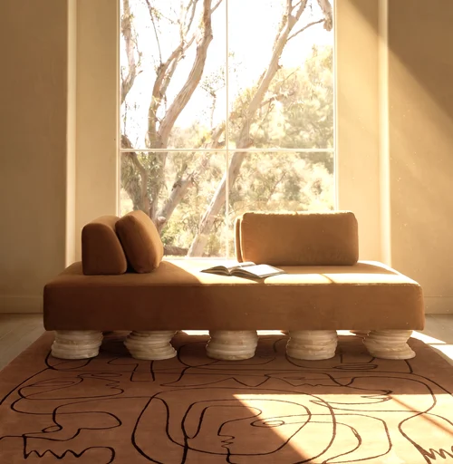 Art + Loom Odette Daybed with camel velvet upholstery and stacked stone legs in a sunlit interior.
