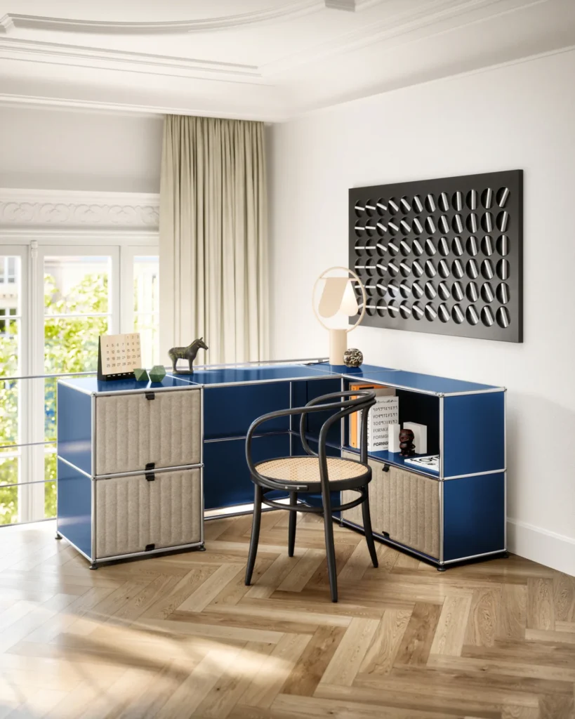 Blue USM Haller desk with beige grooved acoustic panels in a bright home office.