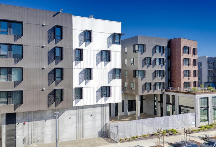Multifamily building exterior with BŌK Modern architectural sunshades projecting from windows across gray, white, and rust-colored façades.
