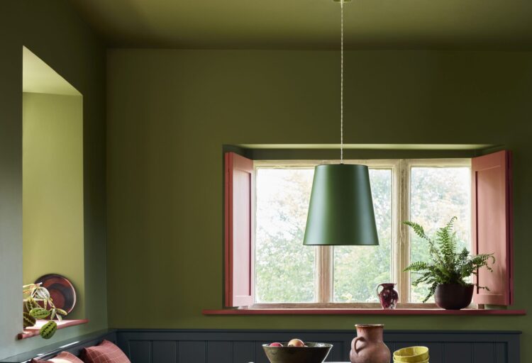 Little Greene olive green interior paint covers the walls and ceiling of a dining nook with contrasting pink window shutters.