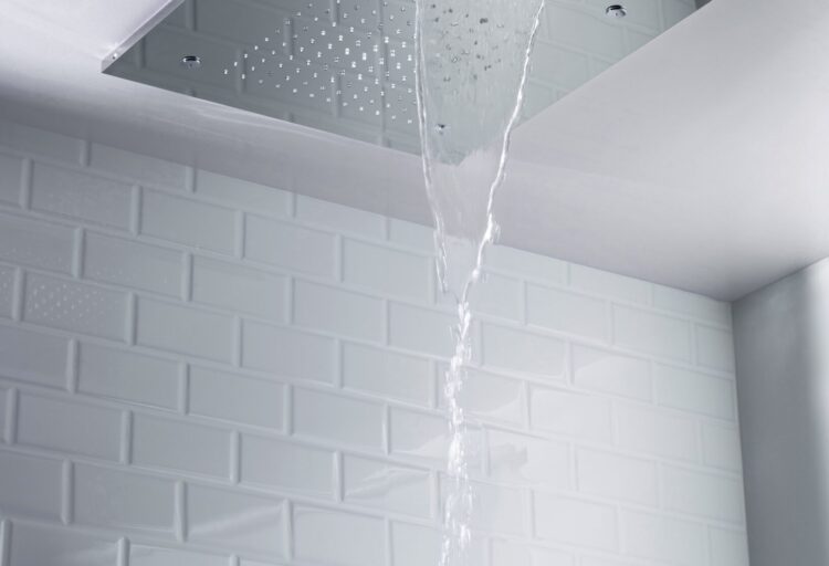 Flusso Cascade flush mount shower head releasing a waterfall from its ceiling-mounted stainless steel plate